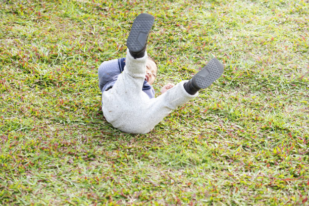 小男孩躺在绿草地上打滚图片下载