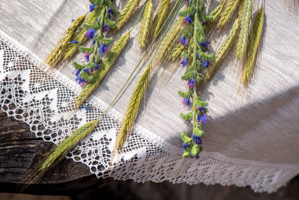 亚麻桌布与钩针白色花边装饰，小麦和鲜花在木制桌子上的照片图片下载