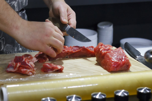 厨师将红牛肉片切在木板上图片下载