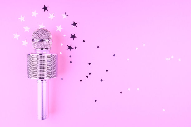粉色背景的麦克风上撒着五彩纸屑。图片下载