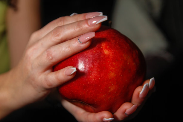 女人用指甲艺术的手拿着红色的大苹果图片下载