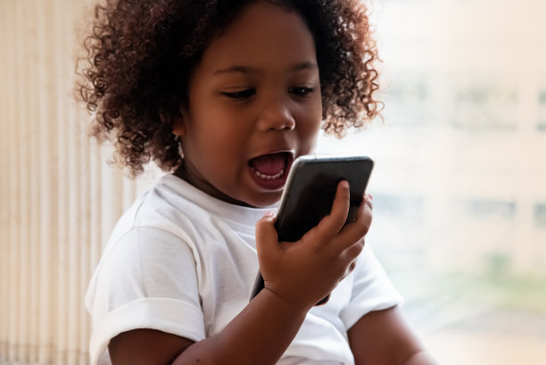 那个卷着头发的小女孩在用手机聊天，快乐的感觉，迷离的灯光围绕图片下载