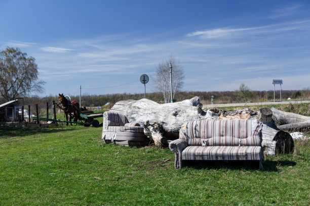 乡村景观，俄罗斯乡村。那张久经风霜的沙发屹立在碧绿的草地上，映衬着骄阳下的蓝天。图片下载