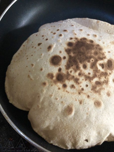 膨胀的烤饼/薄饼在厨房不粘锅里烹饪的照片，全麦阿塔面粉图片下载