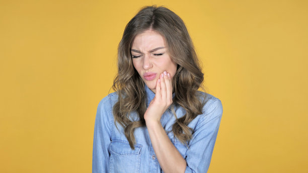 牙痛，年轻女孩牙痛孤立在黄色背景图片下载
