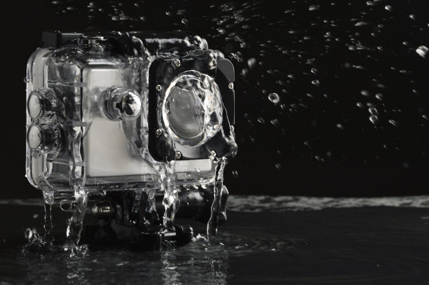 流动的水对防水行动相机在潮湿的黑色石头背景图片下载