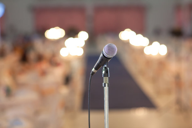 在音乐厅或会议室的麦克风柔和和模糊风格的背景。麦克风上方是会场或会议室背景的抽象模糊照片。图片下载