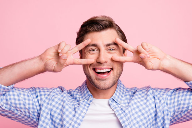 近距离的照片惊人的他，他的男人的手，手指手势，近眼睛说嗨，调情与年轻的女孩女人穿着休闲格子衬衫孤立在苍白的玫瑰背景图片下载