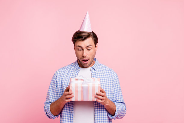 近距离的照片美丽惊人的漂亮，他他英俊的假日帽在头上举着大礼盒想穿着休闲格子衬衫外套孤立在玫瑰背景图片下载