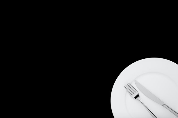 叉子和刀在白色圆形陶瓷板上孤立的黑色背景与复制空间。自顶向下的观点。图片下载