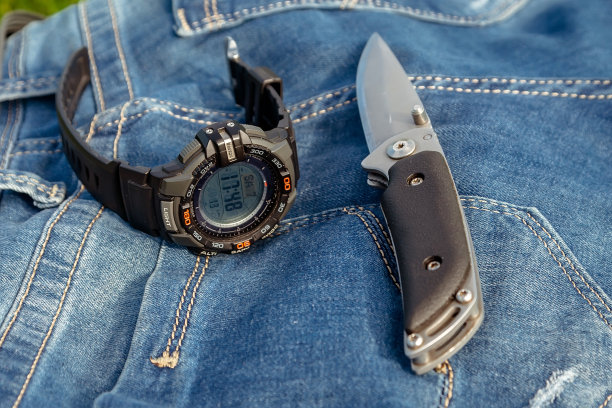 一个锋利的刀和一个时钟在一个牛仔裤的背景在自然界。图片下载