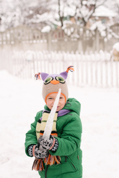 一个拿着冰柱的小男孩的冬季肖像图片下载
