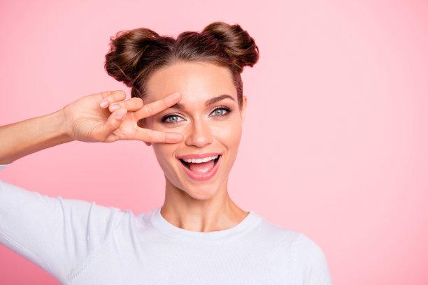 近距离的照片令人惊讶的有吸引力的漂亮，她的女士与可爱的小圆面包显示手指在形状的数字v符号穿着白色套衫孤立在明亮的玫瑰背景图片下载