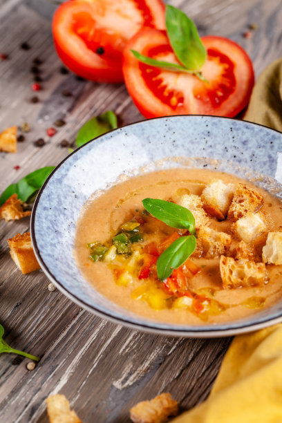 西班牙菜的概念。新鲜西红柿做成的西班牙凉菜汤。在一家餐馆的木桌上，漂亮的上菜盘子装在一个蓝色的盘子里。的背景图片。本空间图片下载