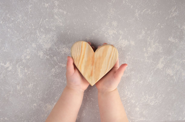 孩子们手里拿着一颗木制的心。情人节。抽象的背景。图片下载