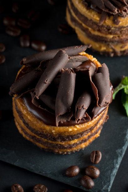 巧克力蛋糕在黑色木板薄荷，咖啡豆在黑暗的背景，特写照片。新鲜、美味的甜品理念。图片下载