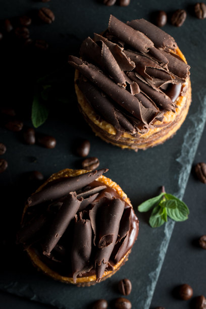 巧克力蛋糕在黑色木板薄荷，咖啡豆在黑暗的背景，特写照片。新鲜、美味的甜品理念。图片下载