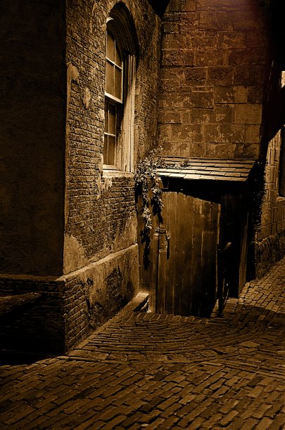 黑暗的小巷，有旧建筑的一部分和通往地下室的门。图片下载