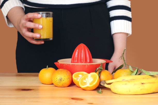特写阿拉伯年轻女子制作新鲜橙汁和饮用果汁图片下载