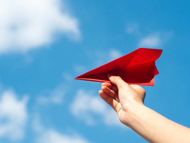 女人手拿红纸火箭与蓝天背景。自由的概念图片下载