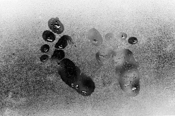 在玻璃上画脚。雾状玻璃的质感。滴在玻璃上。黑白图片。图片下载