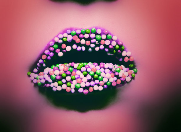 女性嘴唇与彩色糖果特写宏在珊瑚霓虹灯。图片下载