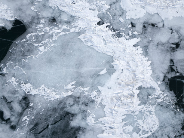 俄罗斯奥尔洪岛冬季结冰的贝加尔湖的航拍照片。深蓝色结冰的湖面上有白色的冰裂缝。图片下载