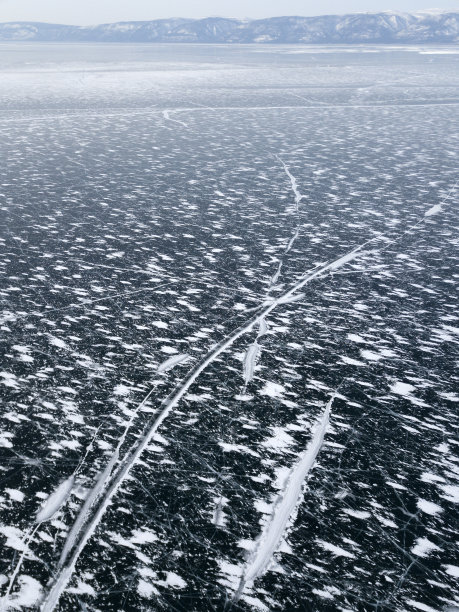 俄罗斯奥尔洪岛冬季结冰的贝加尔湖的航拍照片。深蓝色结冰的湖面上有白色的冰裂缝。图片下载