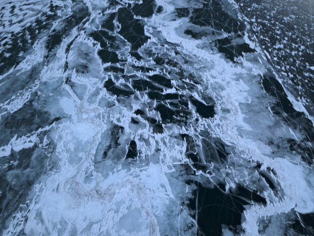 俄罗斯奥尔洪岛冬季结冰的贝加尔湖的航拍照片。深蓝色结冰的湖面上有白色的冰裂缝。图片下载