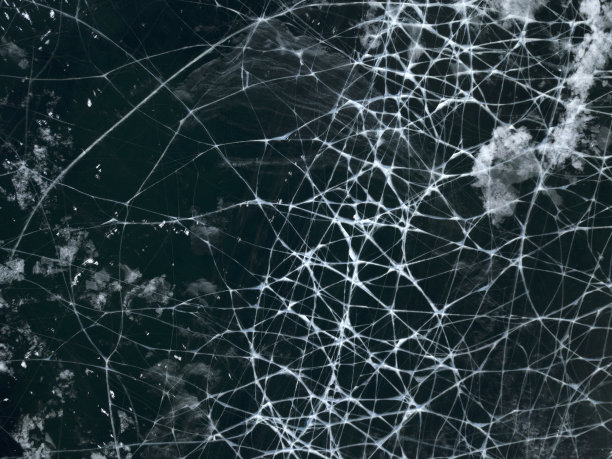 俄罗斯奥尔洪岛冬季结冰的贝加尔湖的航拍照片。深蓝色结冰的湖面上有白色的冰裂缝。图片下载