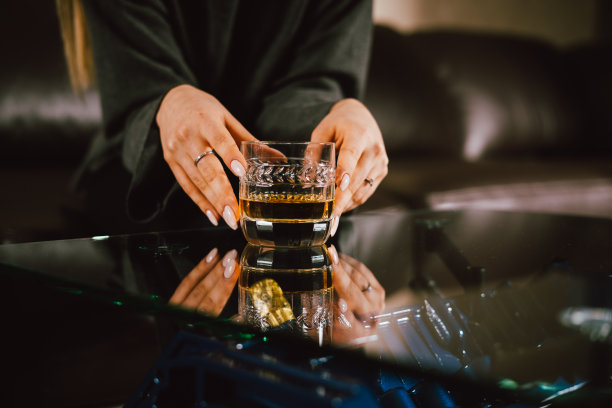 年轻的白种金发女孩坐在沙发上与一杯威士忌在豪华内饰定制v8汽车发动机表。时尚的图片和美丽的微笑图片下载