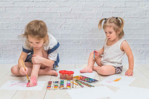 女孩，孩子用画笔和水彩画，在纸上和衣服上作画素材图片