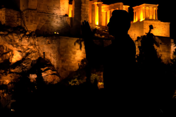 前景是人们的剪影，背景是卫城的夜景图片下载