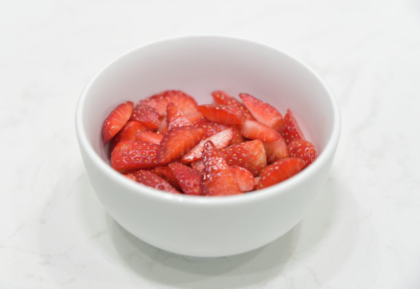 鲜嫩的草莓切片放在白色的碗里，红色的草莓，选择性聚焦，特写。图片下载