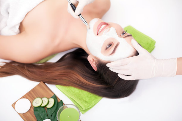 硬件美容。可爱的年轻女人的特写照片与奶油面膜在美容院。图片下载