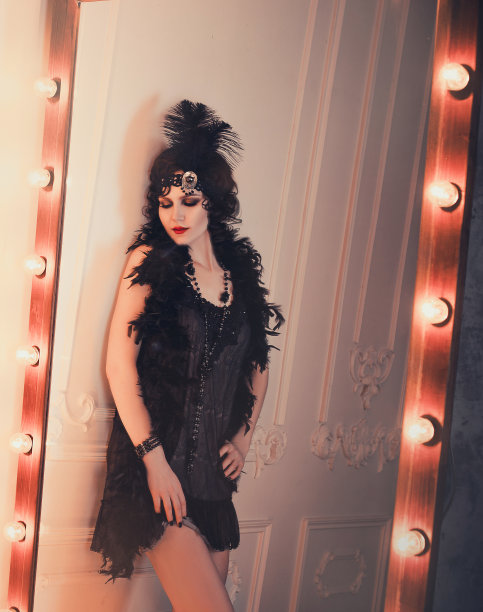 20年代复古风格的优雅女性，穿着黑色连衣裙，黑色头发和绷带，羽毛围巾，长手套。一个黑帮女孩在派对上的形象，老式的。艺术处理图片下载