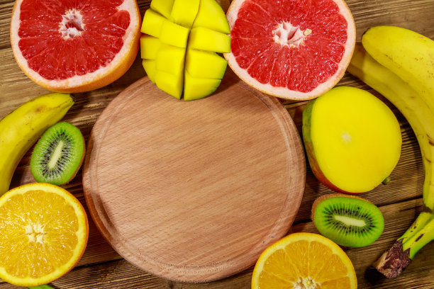 木桌上各种各样的热带水果。有香蕉，芒果，橙子，柚子和猕猴桃的静物画图片下载