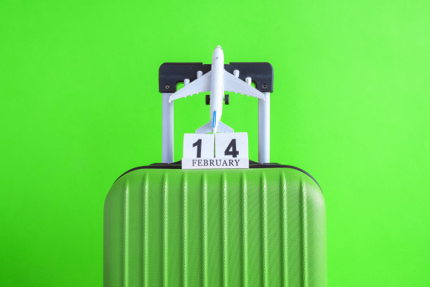 行李与情人节日期日历和飞机在绿色背景的简约度假概念。图片下载
