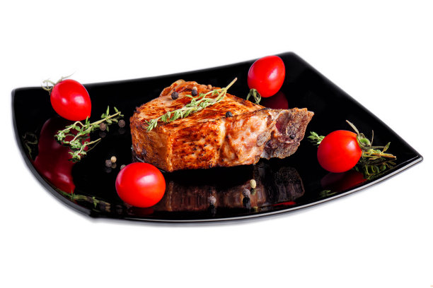 肉与圣女果和黑胡椒一起放在黑色的盘子里。图片下载