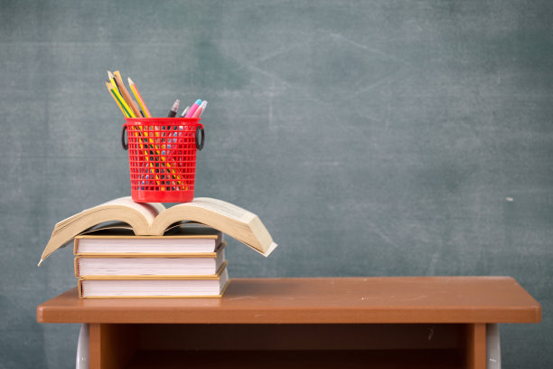 学校课本在课桌上，课本和黑板在木制的背景上，教育理念图片下载