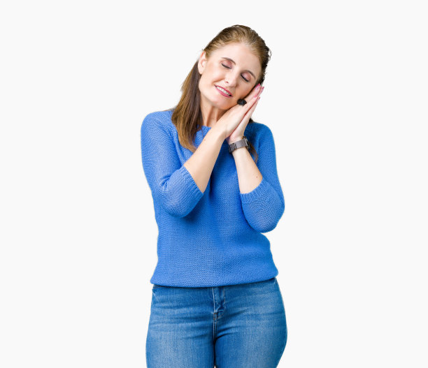 美丽的中年成熟的女人穿着冬天的毛衣在孤立的背景睡累了做梦和摆姿势与手在一起而闭上眼睛微笑。图片下载