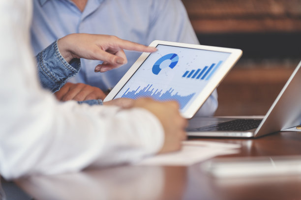 商务人士在数字平板电脑上处理财务数据。图片下载