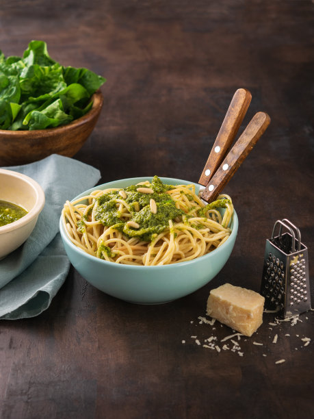 用菠菜香蒜酱、核桃和新鲜生菠菜叶做成的意大利面。黑暗的背景。健康饮食，素食。副本的空间。图片下载
