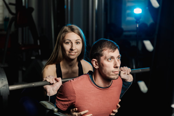 活泼漂亮的健身模特女孩在健身房里坚持蹲着一个运动员图片下载