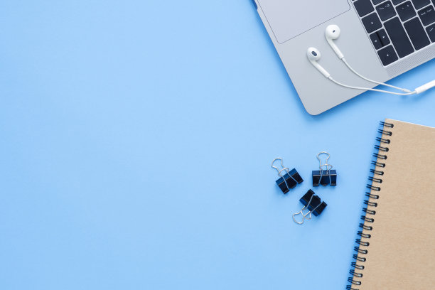 办公室办公桌工作空间-平铺顶视图模型照片的工作空间与笔记本电脑，笔记本和耳机在蓝色柔和的背景。粉蓝色复制空间办公桌的概念。图片下载