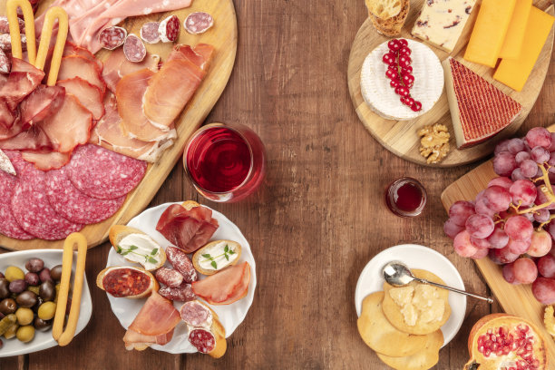 熟食店品尝。许多不同的火腿，午餐肉和奶酪拼盘的照片，从顶部拍摄在一个乡村背景与一杯红酒和复制空间图片下载