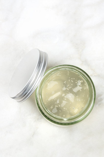 一个装有芦荟胶的玻璃罐的照片，从上面拍摄的白色大理石背景和复制空间图片下载