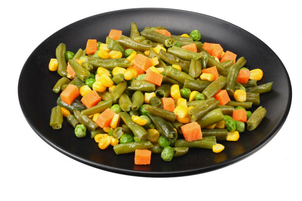 将青豆、青豆和玉米切在黑色的盘子上，在白色的背景上分开。健康的食物图片下载