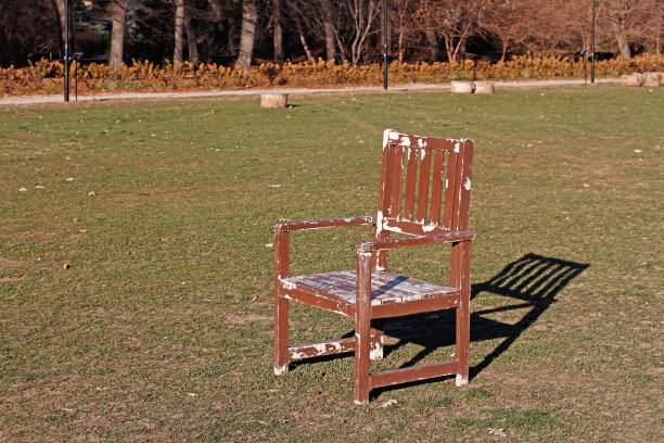 绿草地上放着一把破旧的木椅图片下载