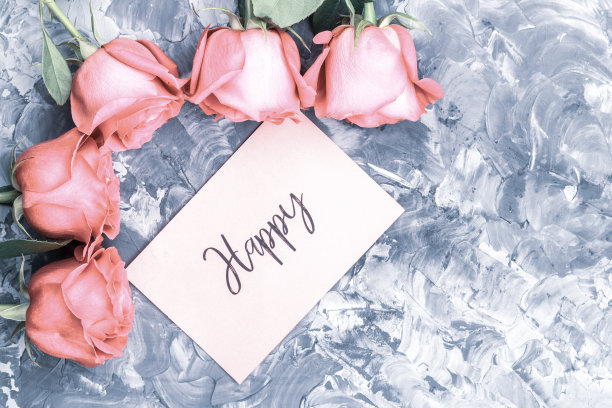 浪漫的概念。灰色混凝土背景上的红玫瑰和“幸福”字样图片下载
